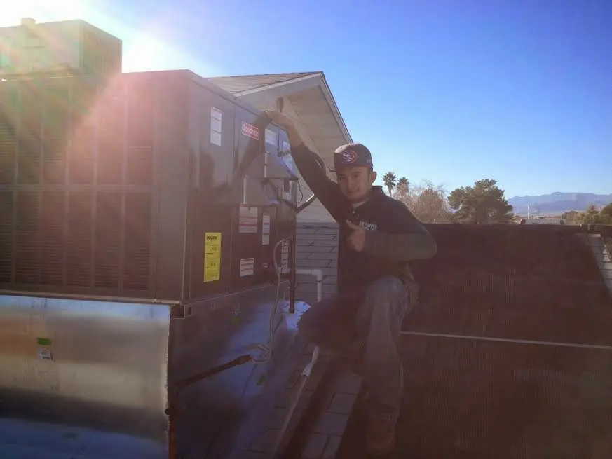 HVAC technician performing AC Tune-Up on a rooftop unit in Oak Creek